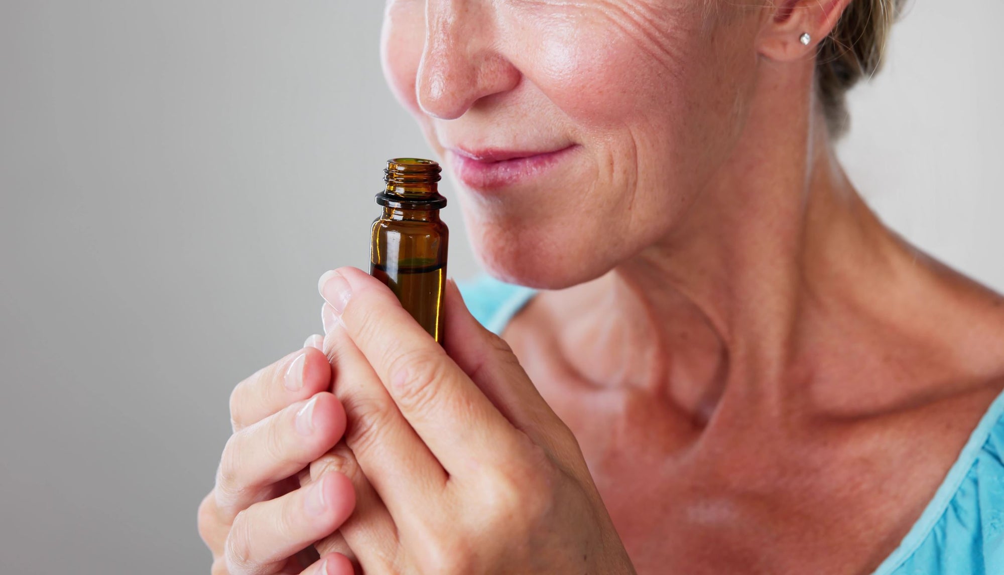 Older woman smelling a 15ml bottle of essential oils